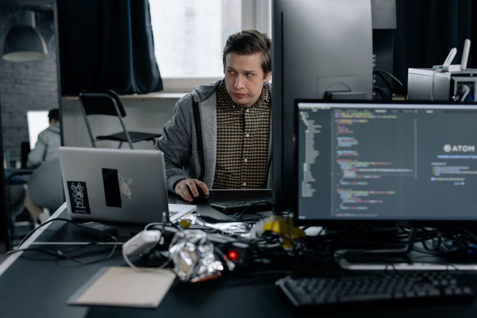 Programer u modernom uredu radi na kodu, prikazuje fokusirano radno okruženje.
